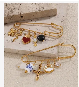 Détail de broches épingles dorées avec pendentifs cœur en émail rouge et agate blanche