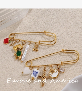 Vue détaillée des broches épingles à nourrice dorées avec pendentifs en émail et perles