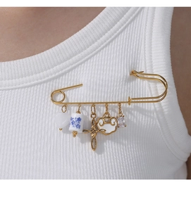 Détail d'une broche épingle de sûreté dorée avec perles en céramique sur tissu blanc