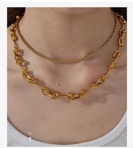 Detailopname van de dubbellaagse 18k vergulde gedraaide ketting en golvende kralenketting