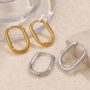 Élégantes boucles d'oreilles ovales dorées et argentées polies sur fond texturé neutre