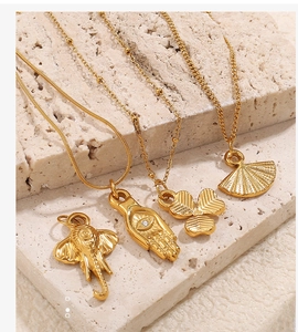 Vista de detalles de dijes chapados en oro de 18K con diseños de elefante y hamsa