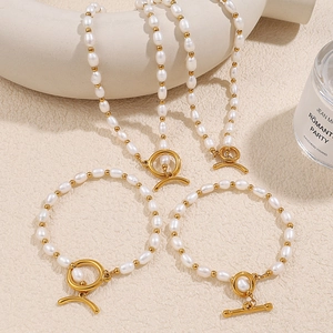 Conjunto de collar de perlas de agua dulce asimétrico con cierre OT dorado sobre superficie