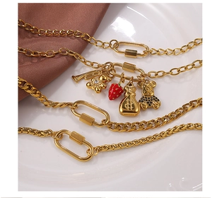 Détail d'un collier doré multi-chaînes avec ours, fraise et pendentifs porte-monnaie