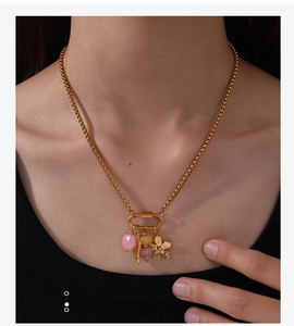 Vue détaillée du collier à maillons dorés avec breloques plume, fleur et perles