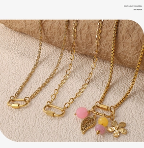 Détail de colliers dorés avec pendentifs floraux roses et fermoirs mousquetons design