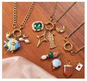 Λεπτομέρεια από χρυσά μενταγιόν με σμαράγδι, μαργαριτάρι και φυλαχτά σε ξύλο
