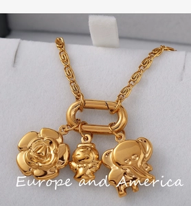 Vue macro d'un collier doré avec pendentifs rose, ange et éléphant sur chaîne en S