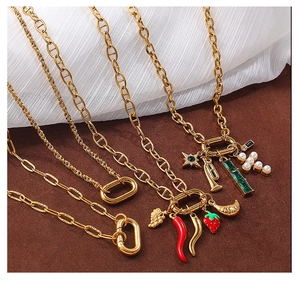 Detail of gold chain necklaces featuring red chili, strawberry, and pearl cross charms