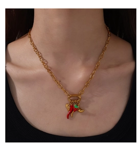Detail of gold chain necklace with red chili, strawberry pendants on a female model