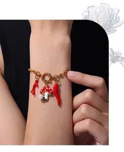 Detalle de pulsera de cuentas doradas con colgantes de coral, hongo y chile rojo