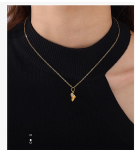 Detailed close-up of a gold shell pendant with micro-set zircons on a delicate chain necklace