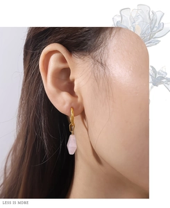 Détail de boucles d'oreilles dorées avec pendentif en cristal rose sur un mannequin