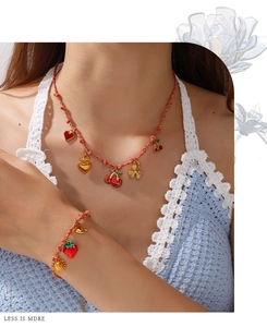 Detalle de conjunto de joyas de cordón rojo con dijes de oro de 18K y esmalte en modelo