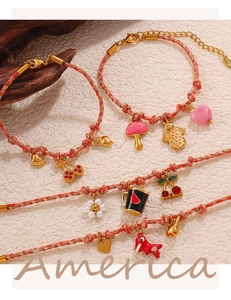 Detalle de pulseras tejidas con colgantes de esmalte de fresa, cereza y corazones