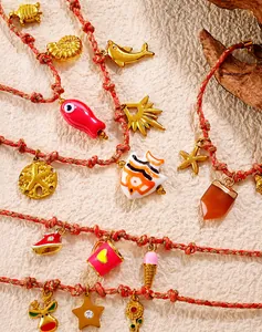 Detalle de cuerdas trenzadas con dijes bañados en oro de 18K como animales marinos y frutas