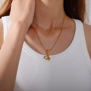 Double layered gold necklace featuring enamel camera and square metal card charms