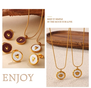 Detail view of 18K gold plated heart and bee necklaces with red enamel and pearl inlay
