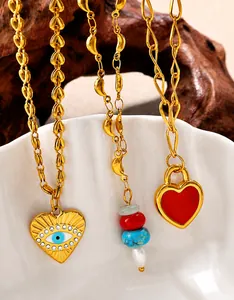 Detail of 18K gold plated necklaces featuring enamel heart and evil eye charms