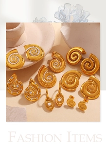 Detail of 18K gold plated spiral earrings with pearls and crystals on stone background
