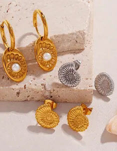 Macro shot of 18K gold plated nautilus shell earrings with pearls on stone texture
