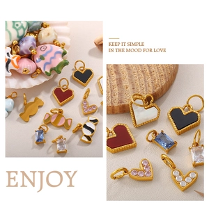 Macro detail of 18K gold-plated fish charms and heart pendants with enamel inlays