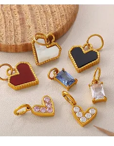 Flat lay of diverse gold-plated heart and rectangular charms on a textured leather background