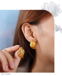 Macro detail of gold seashell earring with tiny zircon stones and spiral texture