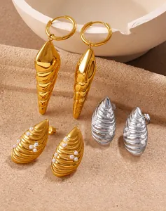 Macro detail of 18K gold-plated shell earrings with pearls and spiral conch charms