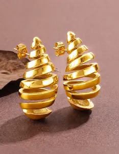 Macro shot of gold spiral shell earrings with polished metallic rings and ear studs