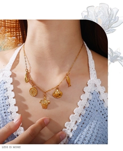 Detailed view of ocean-themed gold charms on a necklace worn on a beach vacation