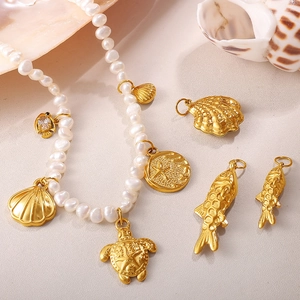 Chic ocean theme pearl necklace with gold sea turtle and starfish charms on beach sand