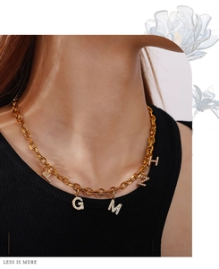 Close-up of 18K gold plated chunky chain necklace with five rhinestone letter pendants