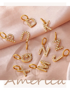 Close-up of sparkling 18K gold plated alphabet pendants with cubic zirconia on pink silk