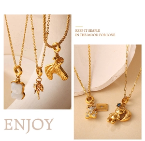 Detailed view of 18K gold plated necklaces featuring bear and angel charms on stone texture