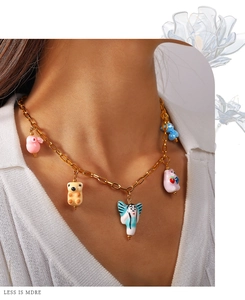 Close-up of golden chain necklace with colorful ceramic animal pendants on a model