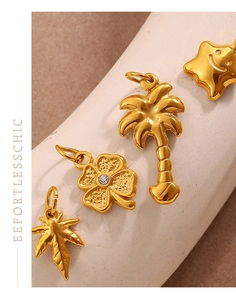 Macro detail of four gold DIY charms featuring palm tree, clover, star, and maple leaf motifs