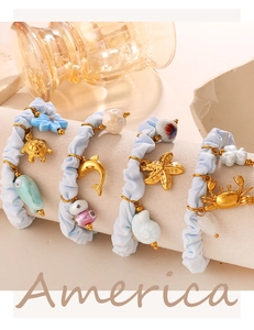 Close-up of four light blue fabric scrunchies with golden sea animal charms like turtles