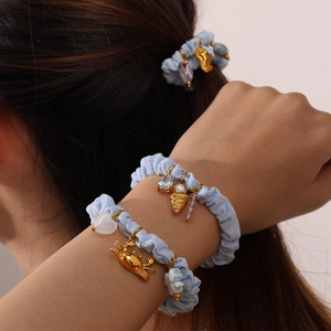 Light blue scrunchie set with golden crab and heart charms worn on wrist and hair