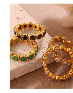 Set of four gold-plated eternity rings with colorful round-cut gemstones on stone