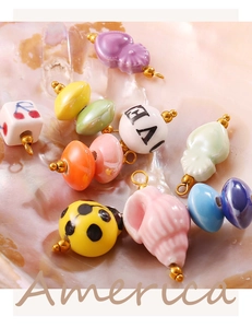 Macro shot of colorful ceramic pendants with golden metal rings in heart and beetle shapes