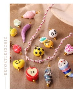 Close-up of handmade ceramic pendants featuring apple, chili, and ladybug designs