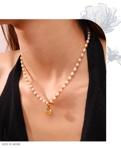 Dettaglio della collana di perle con ciondolo a fungo in smalto colorato al collo