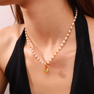 Collana chic di perle e grani d'oro con ciondolo a fungo a pois indossata da una modella