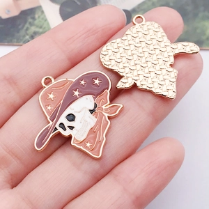 Detailed macro view of cowboy skull alloy charms showing front enamel and back metal texture