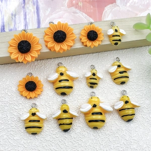 Détail de breloques tournesol et abeille en résine avec anneaux pour bijoux artisanaux