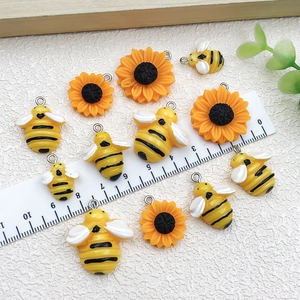 Vue macro des pendentifs abeille et tournesol en résine avec anneaux et règle de mesure