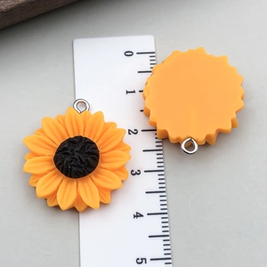 Détail macro de pendentifs tournesol en résine avec anneaux pour création de bijoux