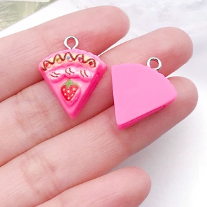 Macro shot of miniature pink strawberry cake resin pendant with silver hook for DIY crafts