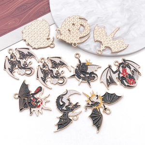Close-up of enamel dragon and moon alloy charms with golden mesh back on marble surface